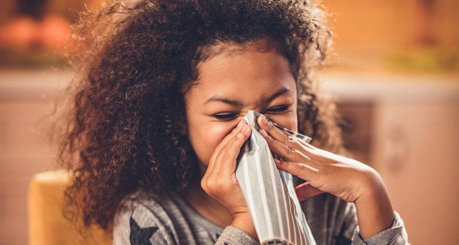 Preventing illness in kids: a girl blows her nose into a tissue