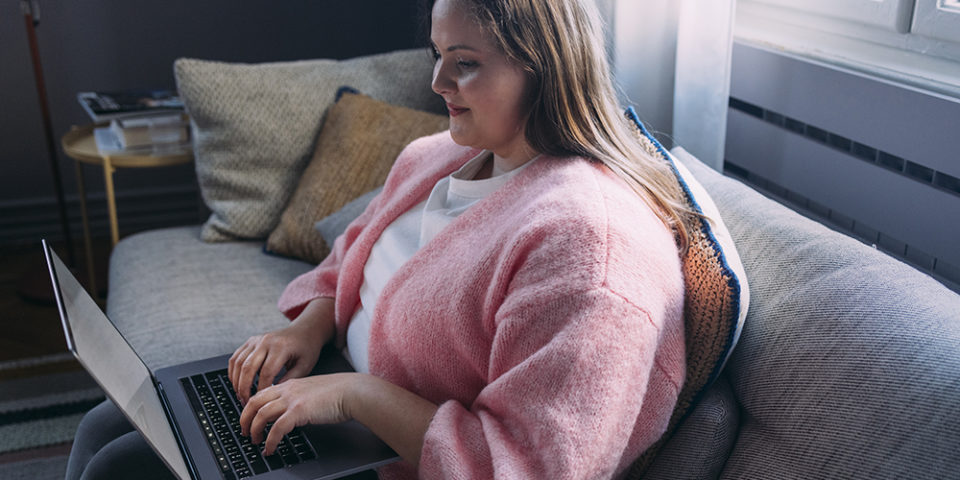 Plus size woman looking at her laptop while reading about weight loss surgery guidelines